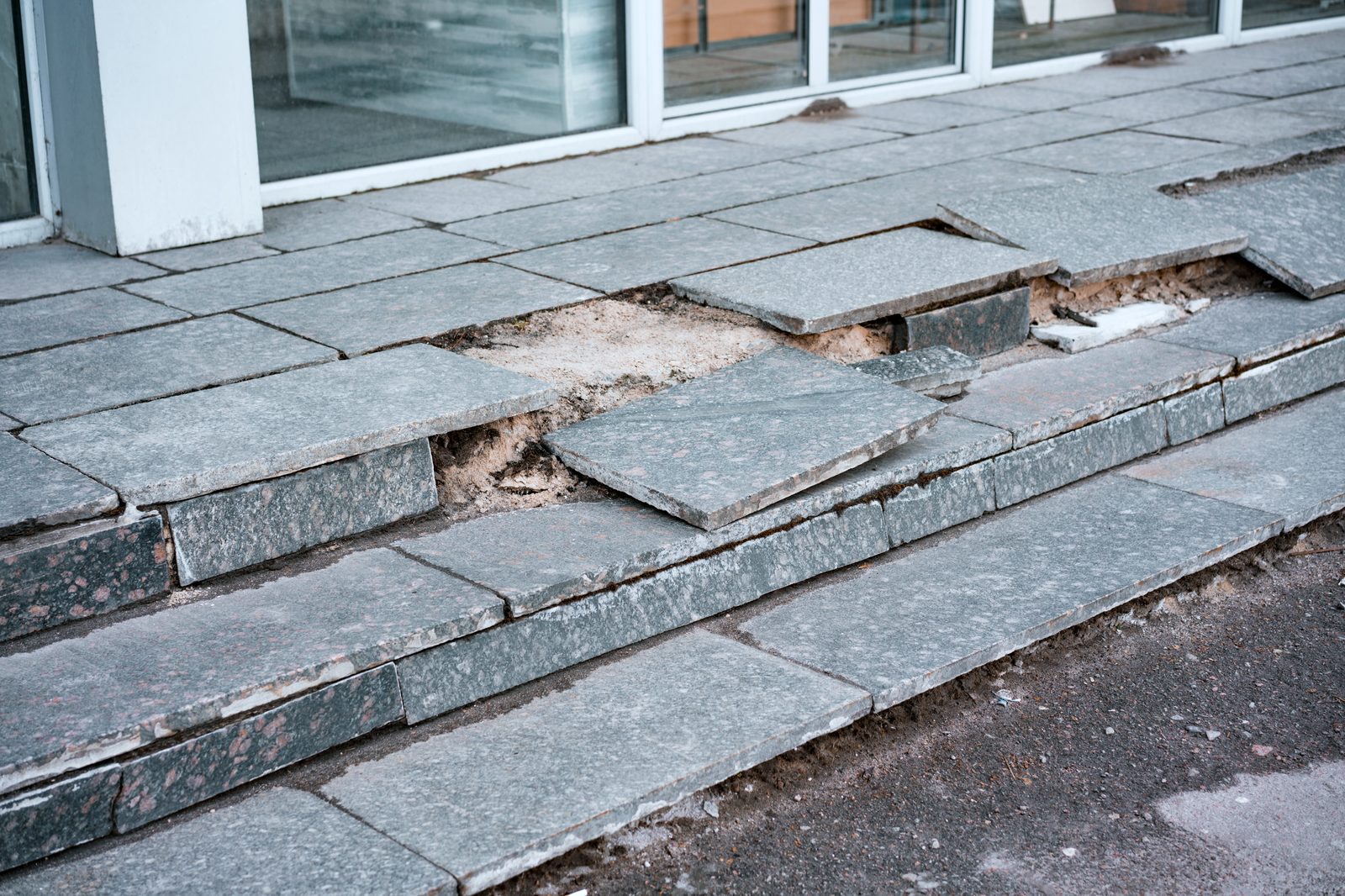 Broken and crumbling outdoor tile stairs at a building entrance